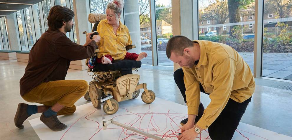 Three people, one a wheelchair user, creating a drawing